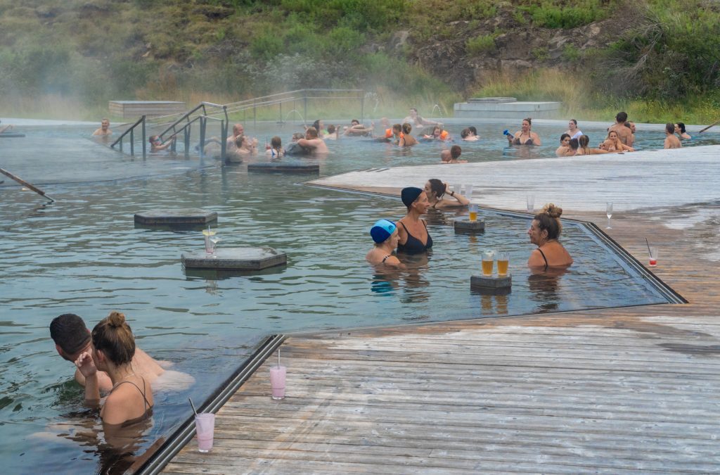 People swimming in a hot pool next to a wooden deck.