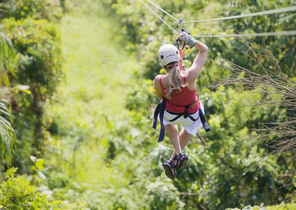 A woman ziplining into the jungle.