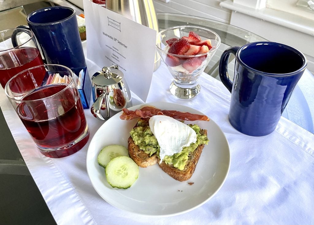 A plate of avocado toast topped with a poached egg and crispy pancetta.