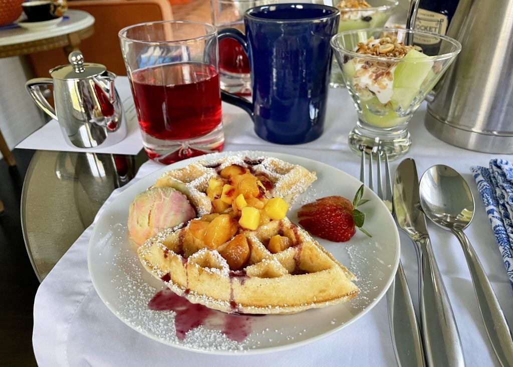 Waffles topped with berries and rainbow sherbet.