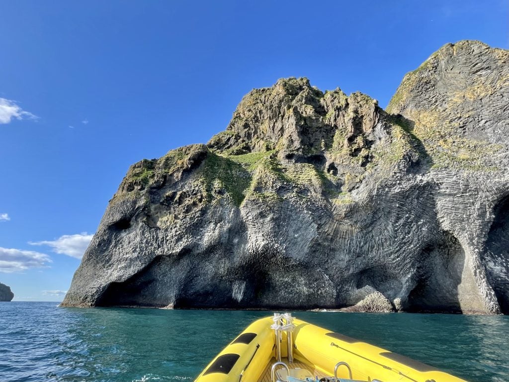 A giant gray rock shaped like an elephant plonking its trunk into the water.