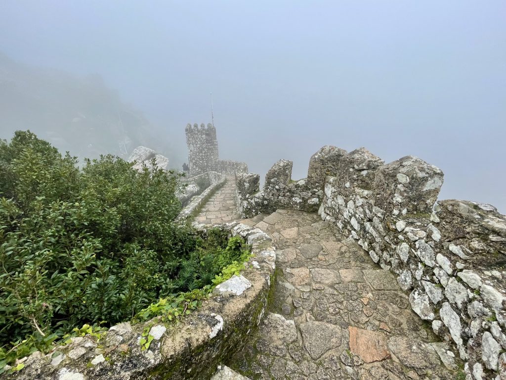 Ruins of the medieval-era Moorish Castle in Sintra, surrounded by fog.