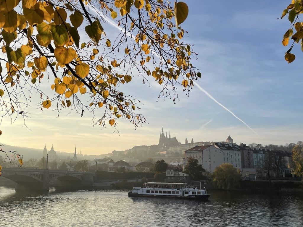 A city skyline with foggy Prague castle along the river, part of the sky blue but fog covering everything.