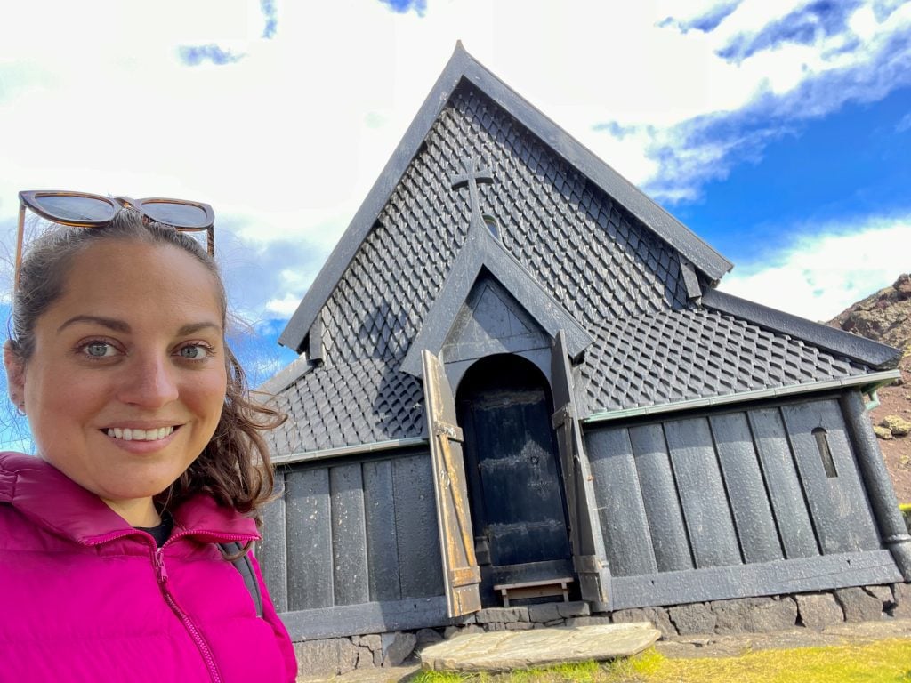 Kate taking a selfie in front of an ornate all-black wooden church.