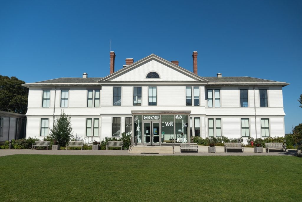 A huge white mansion on a large lawn.