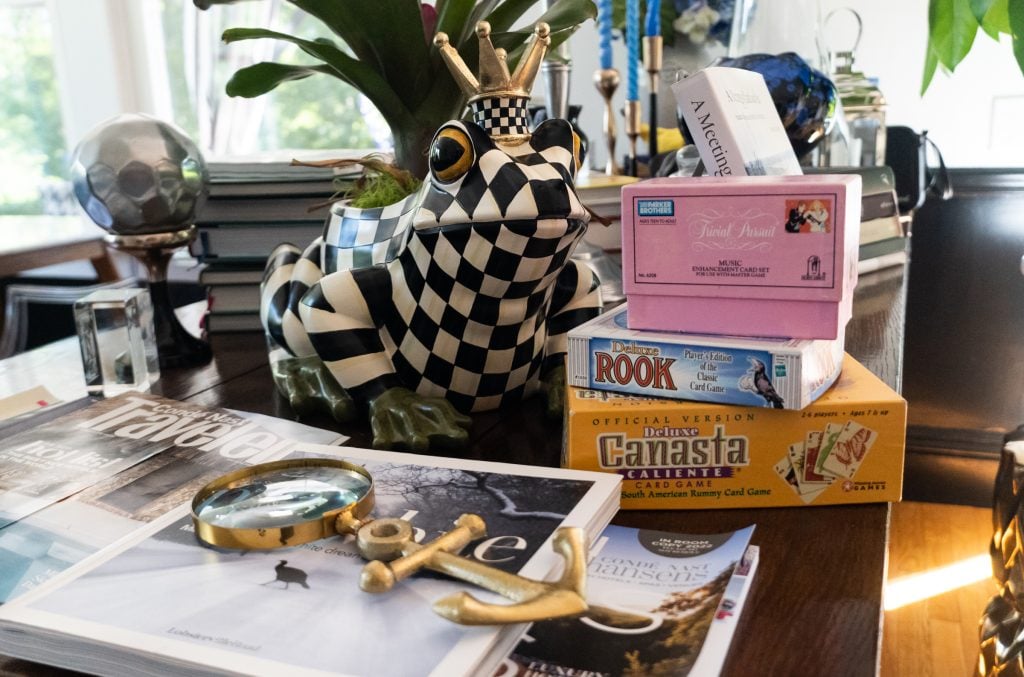 Board games stacked in a pile next to the state of a checkered frog wearing a crown.