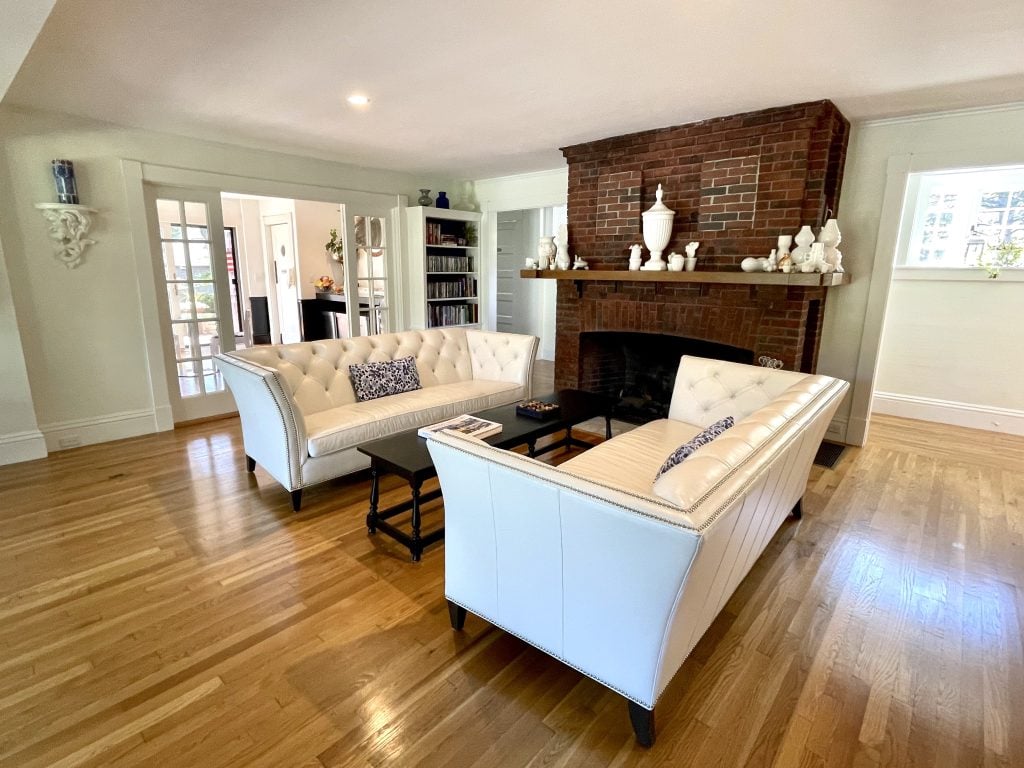 A living room with two modern white leather couches facing each other next to a fireplace.