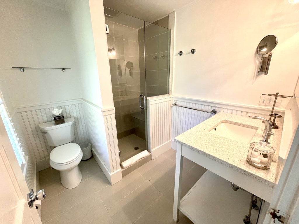 A clean, modern, all-white bathroom with a glass-door shower.