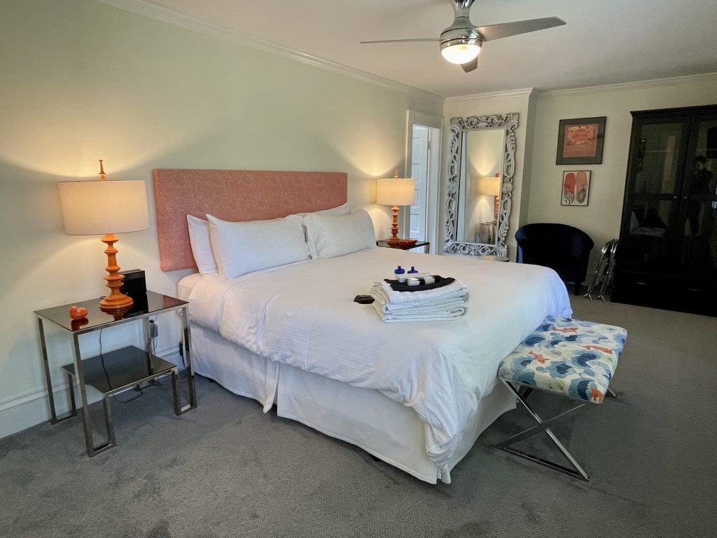 A modern bedroom with a comfortable-looking white bed and lots of orange touches in the decor.