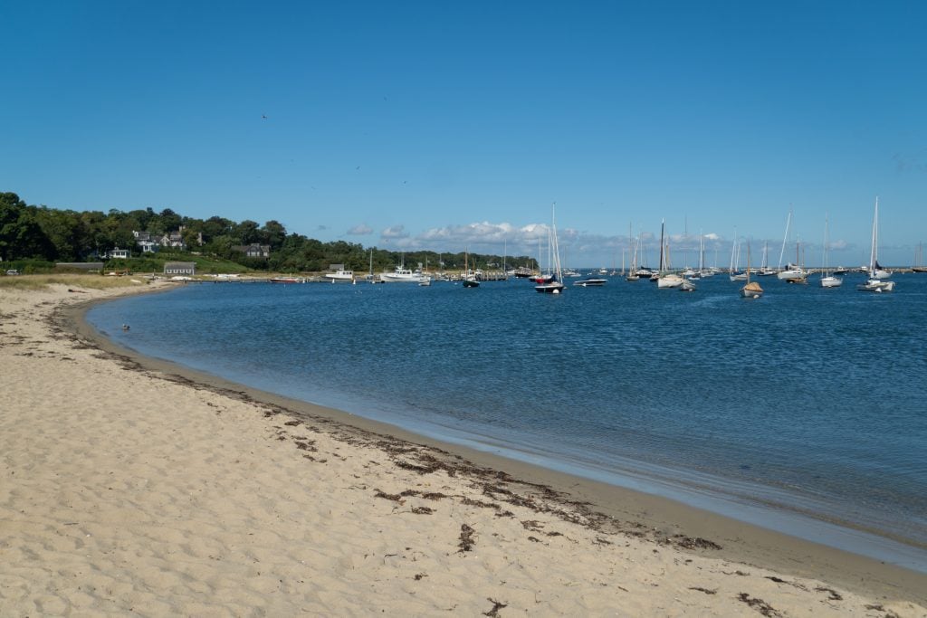 A long, curved beach with calm blue water.