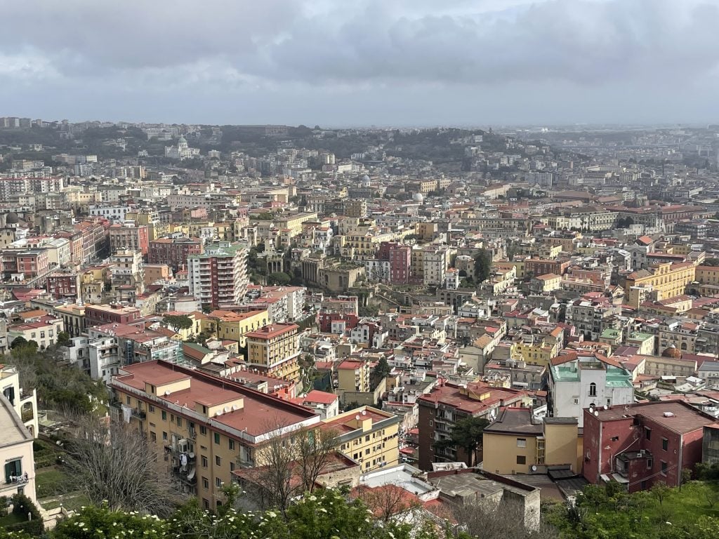 The view of Naples from above, colorful roofs and buildings receding into the distance.