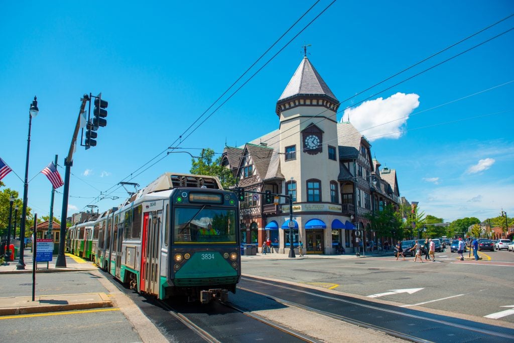 A Tudor building with an old-fashioned turreted tower, and a green line streetcar in front of it.