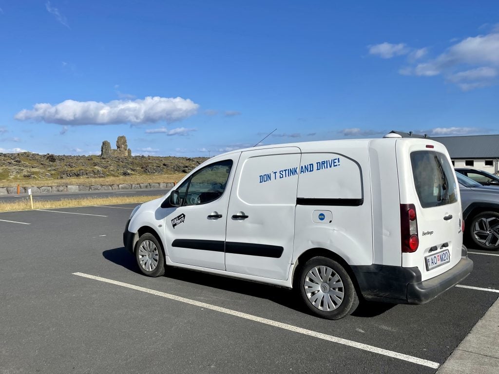 A white camper van with "Don't stink and drive!" stamped on the side.