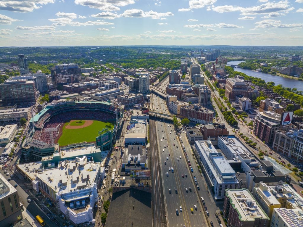 An aerial view of Fenway Park, the famous Citgo sign, lots of buildings, and the highway running through it all.