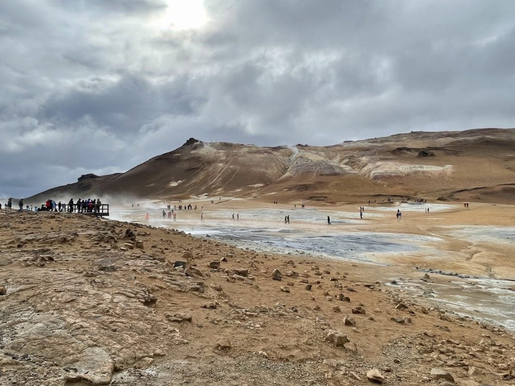 A brown moon-like landscape with lots of cracks emitting steam.