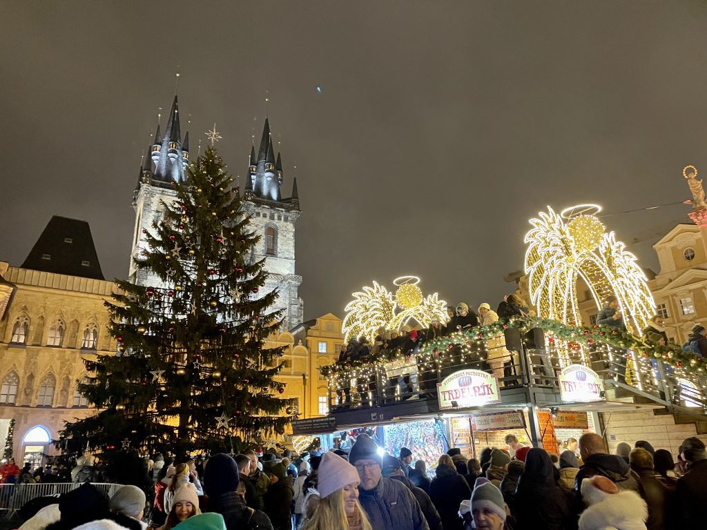 The Prague Christmas markets, with viewing platform in front of a Christmas tree and church towers.