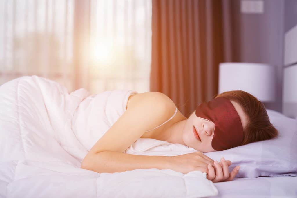 A woman sleeping with a face mask on.