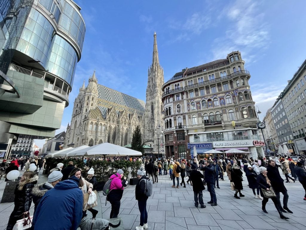 A cathedral in Vienna surrounded by modern buildings and blue sky.