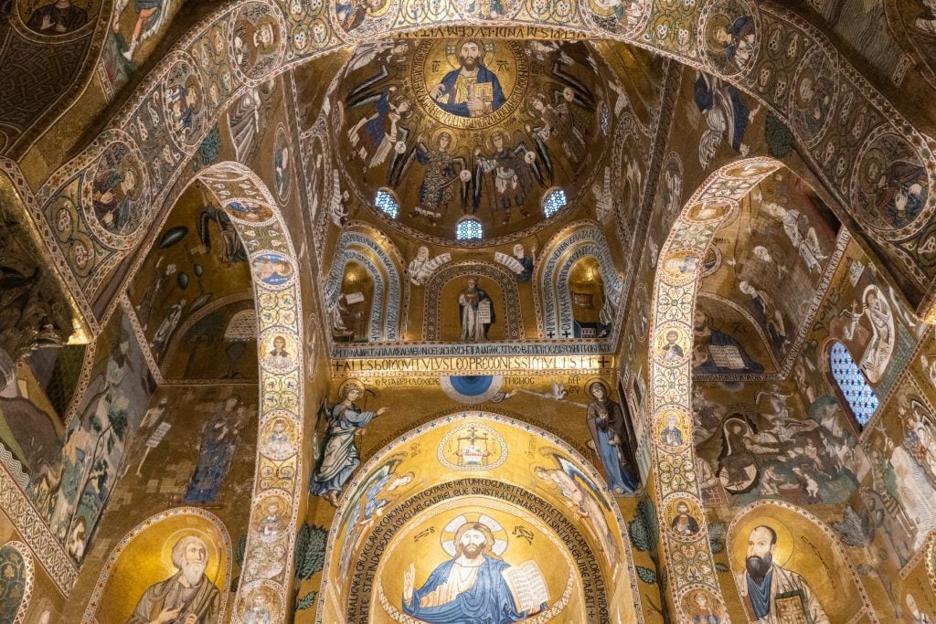 A chapel covered with curving ceilings topped with golden mosaics and images of Christ and the apostles.