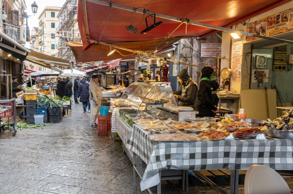 A street market in Sicily with people selling food items.