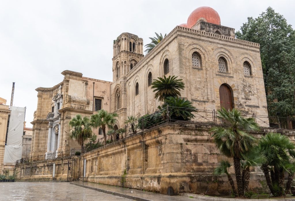 A square stone church topped with unusual red domes.