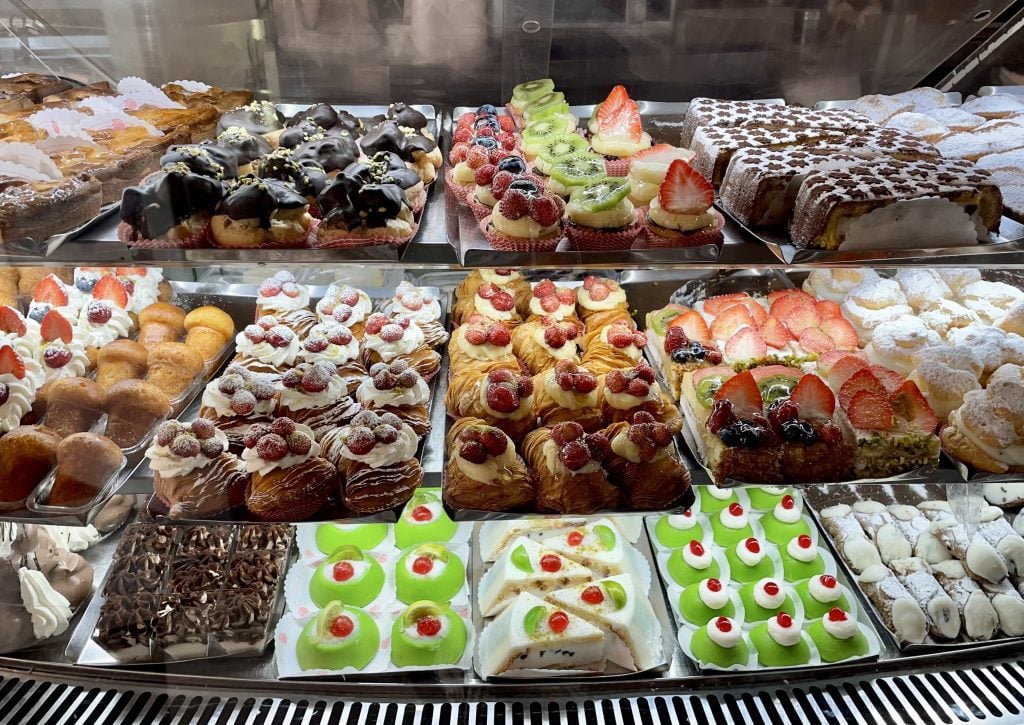 A pastry case filled with dozens of different brightly colored Sicilian pastries.