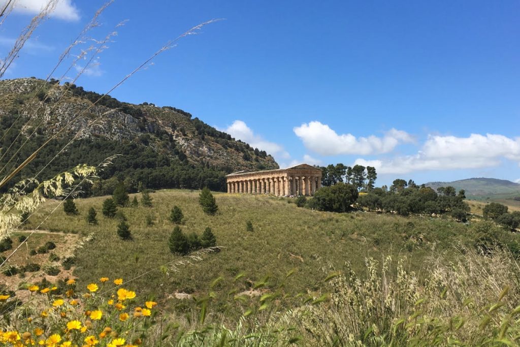 The temple of Segesta from a distance across a field on a bright summer day