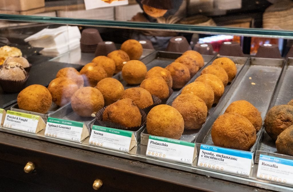 A cafe with rows of softball-sized aracini rice balls.