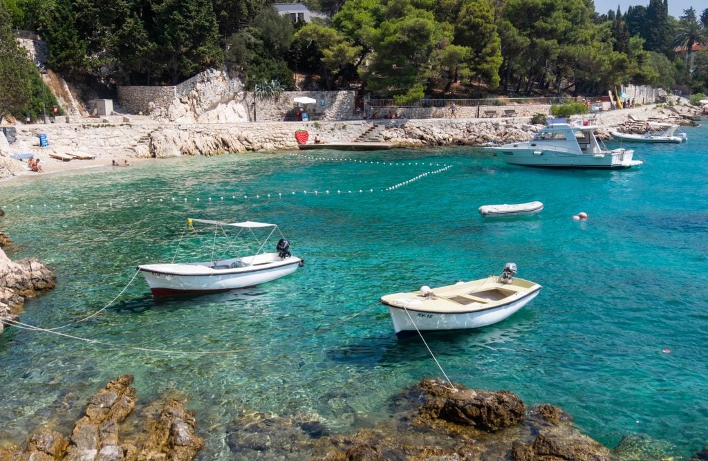 White speedboats moored in a bright teal bay.