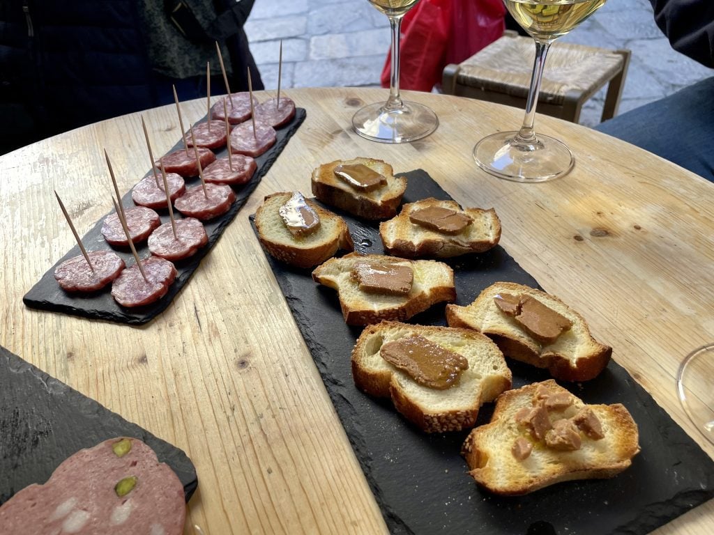 Sicilian small plates: a plate of sausage and a plate of crostini topped with slices of bottarga.