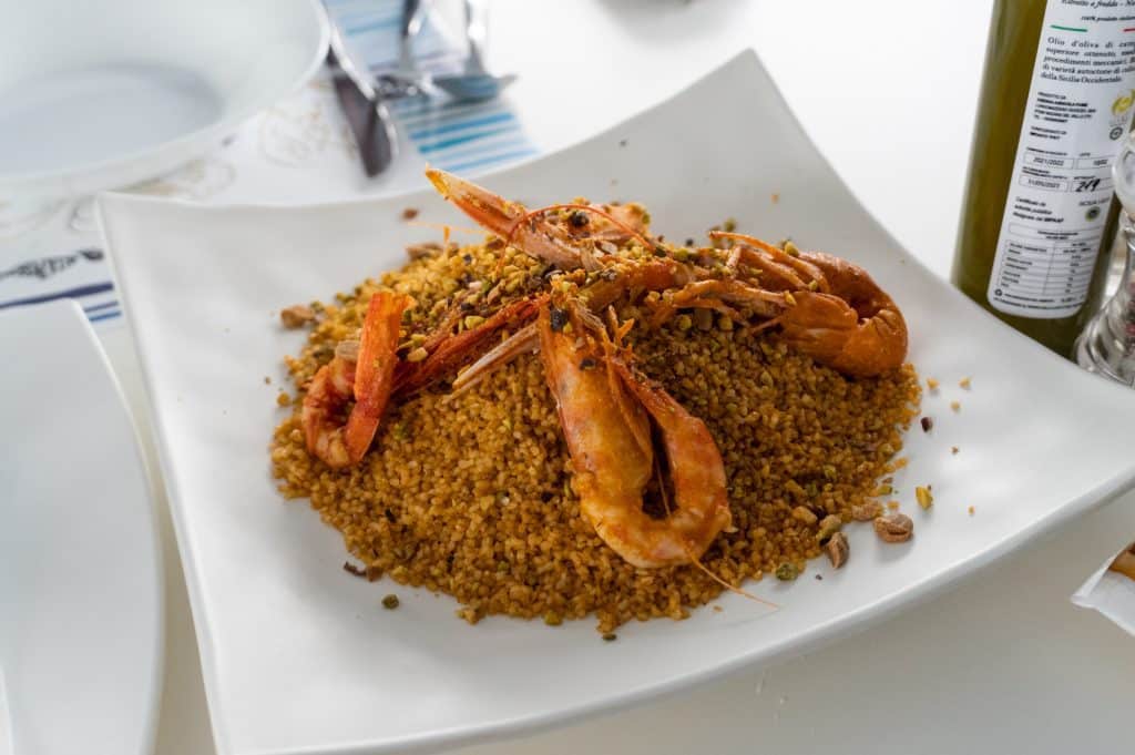 Four large red shrimps on a pile of couscous.