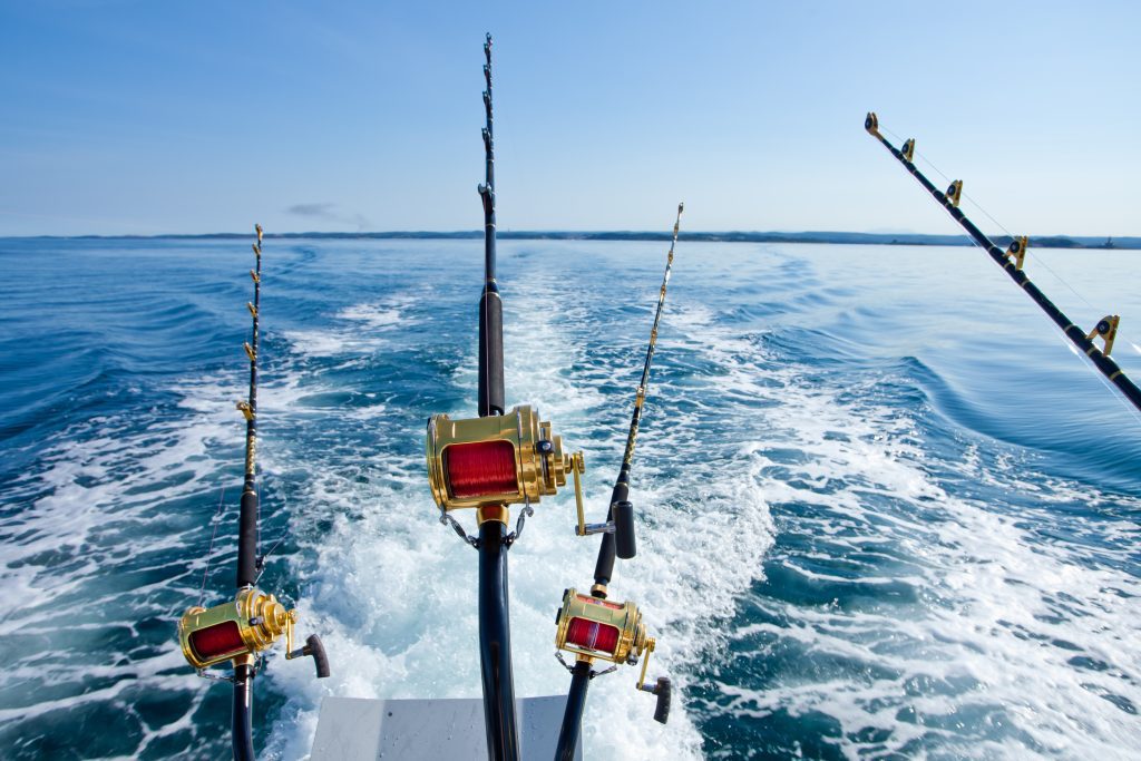 Fishing poles off the edge of a boat on the sea.