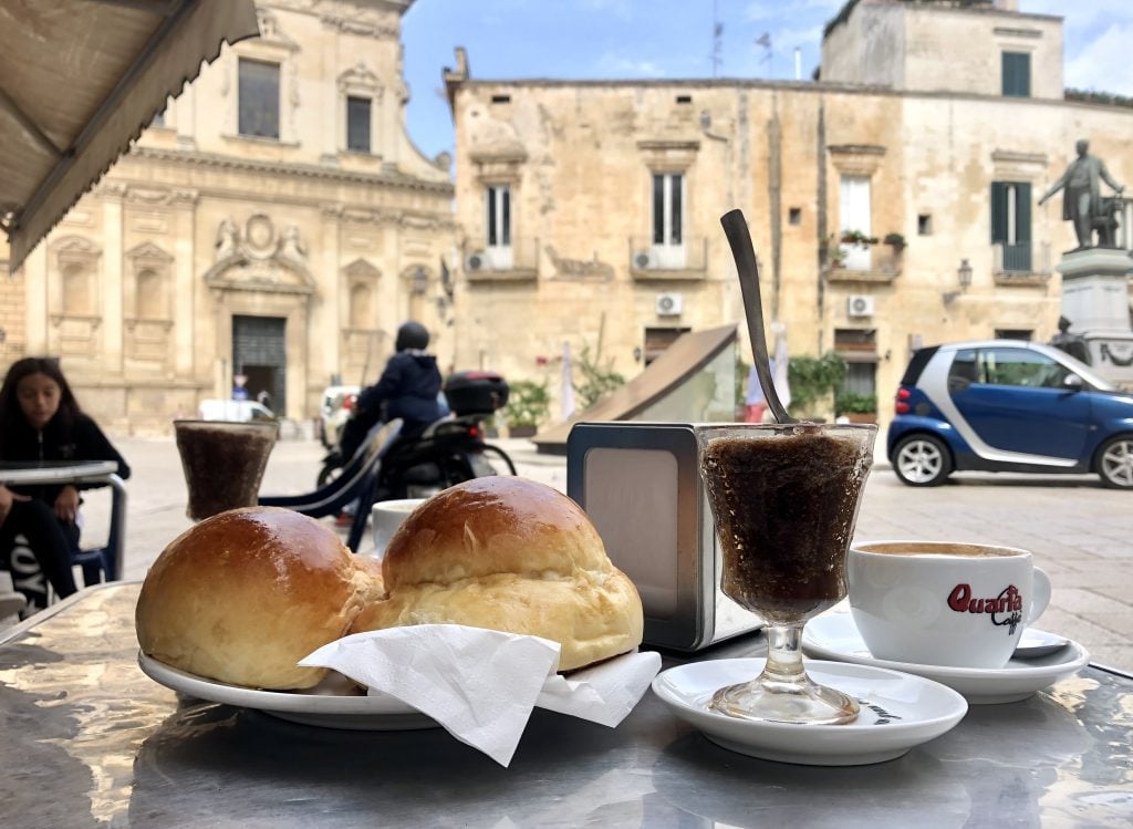 Two dark brown granita glasses next to two plump brioches.