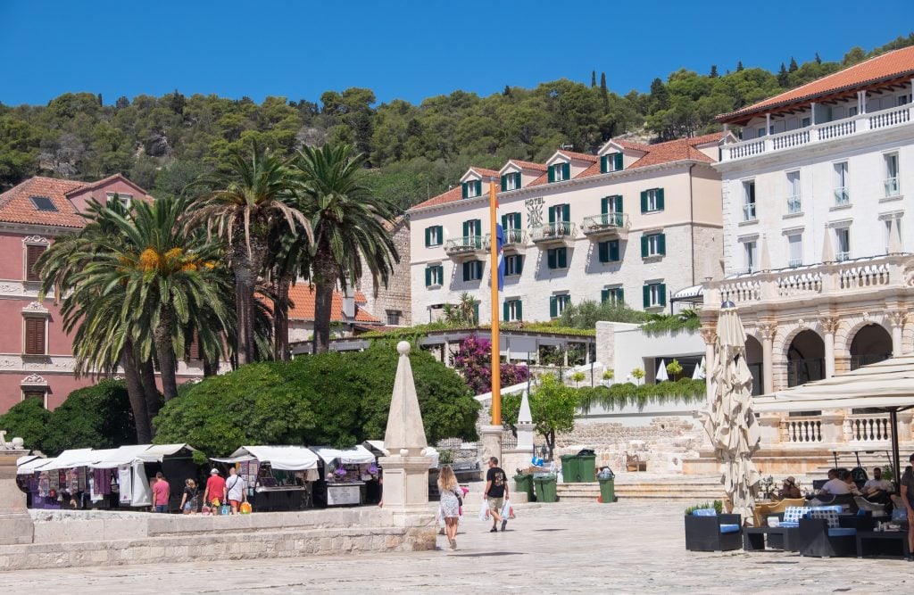 A stone old town with bright, tall hotels and palm trees.