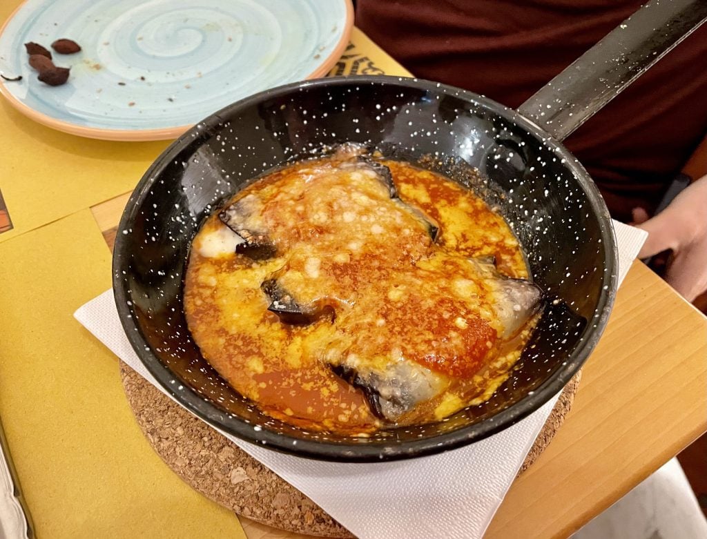 A skillet filled with eggplant, tomato sauce and cheese.