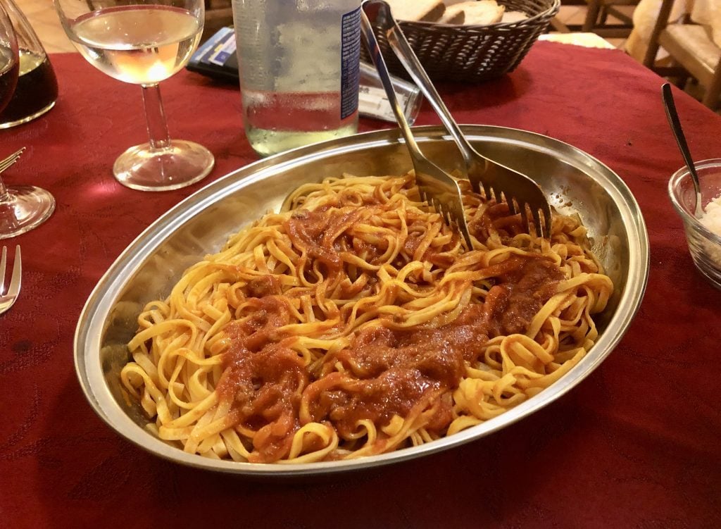 A big bowl of spaghetti covered with marinara sauce.