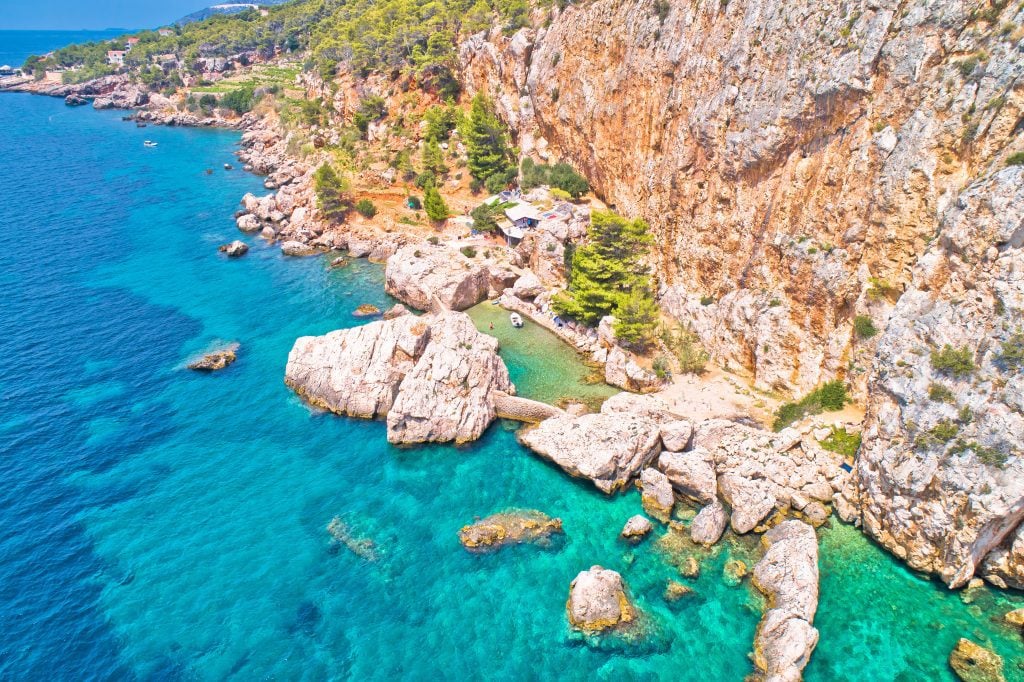 The rocky Croatian coastline on top of neon blue-green water.