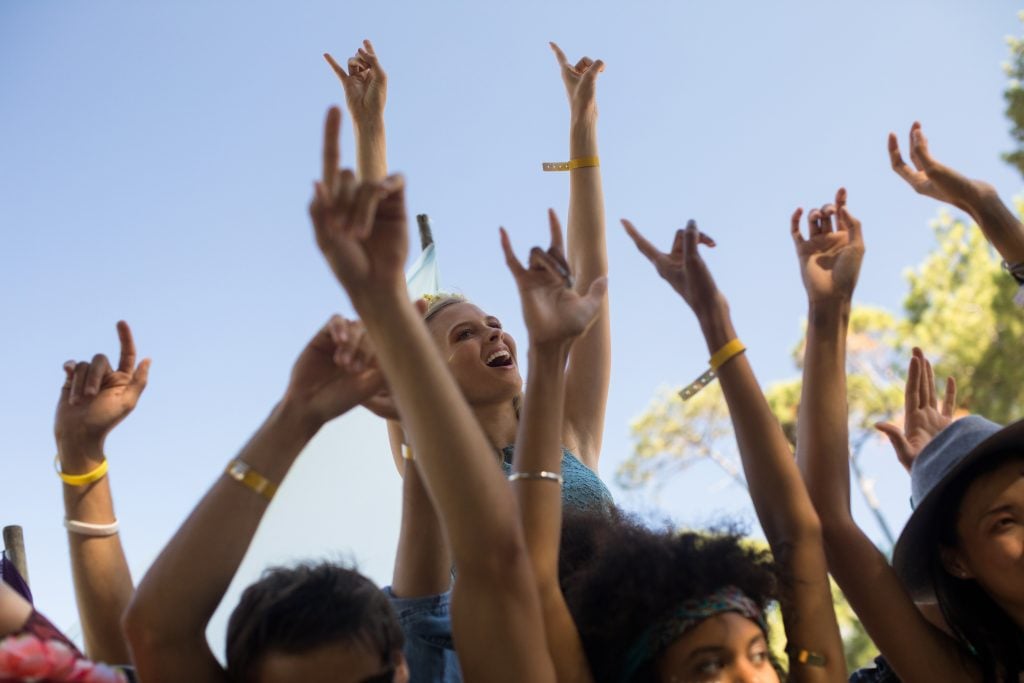 People dancing in a group with their hands in the air.