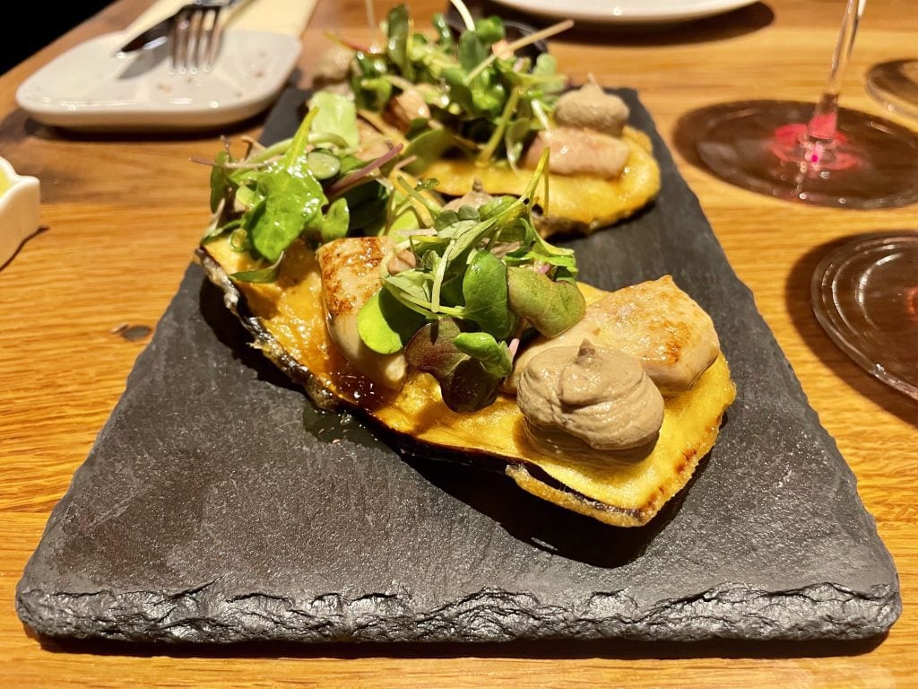 Pieces of eggplant topped with various pastes and green herbs.