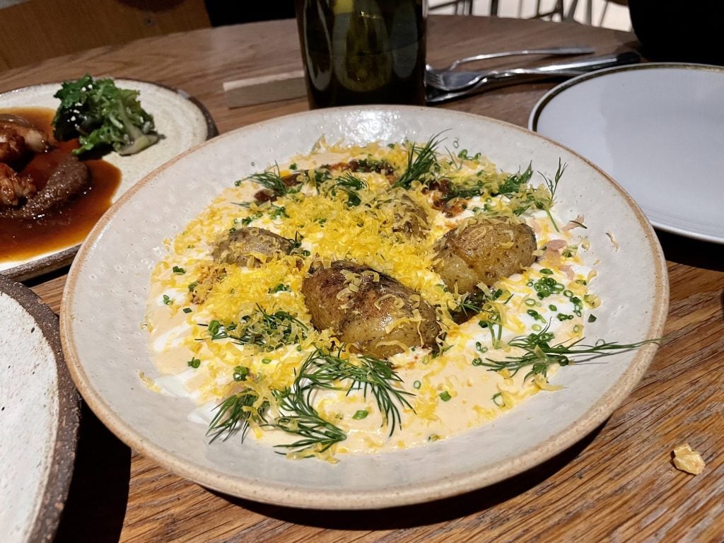 Potatoes in a thick yellowish soup, topped with chives and dill, and egg yolk shavings.