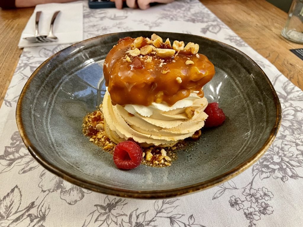 A HUGE cream puff stuffed with multiple layers of cream and topped with caramel, hazelnuts, and raspberries.
