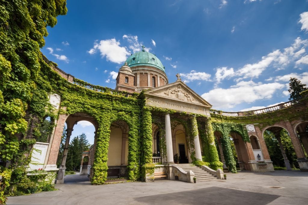 A building lined with green columns covered with ivy.