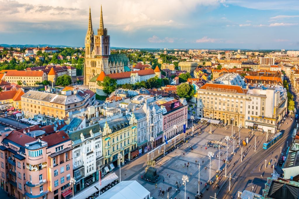 A skyline view of Zagreb, sun dappled on brightly colored buildings and church steeples.