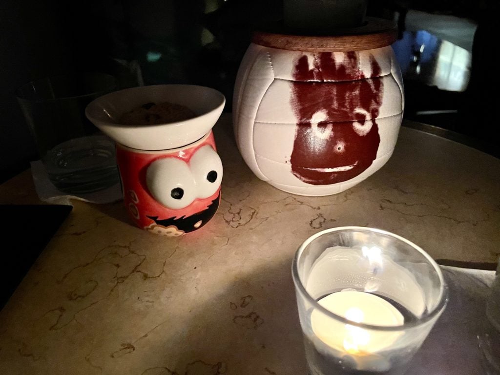 Two cocktails: one in a cup shaped like the head of Elmo, and one shaped like Wilson the volleyball from Cast Away with a bloody handprint.