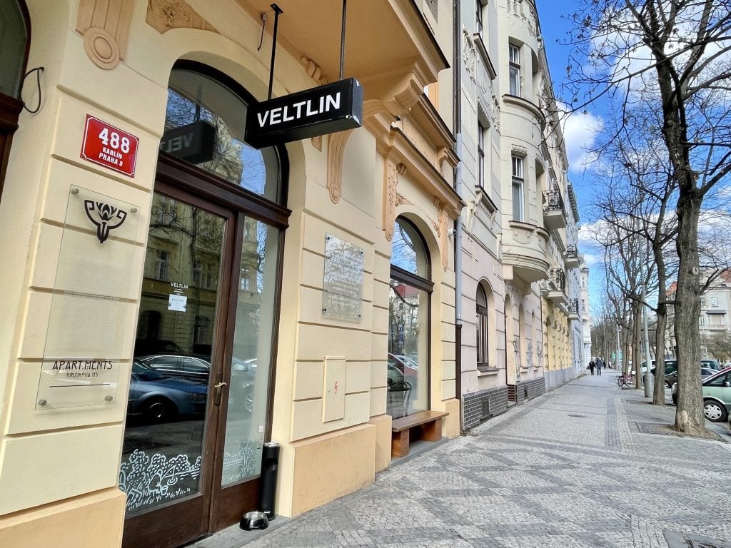 A colorful street with the bar's sign reading Veltlin hanging from above.