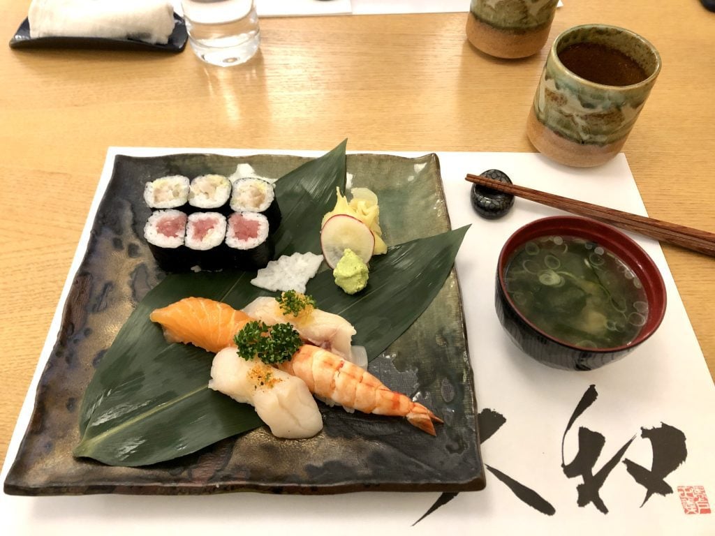 A platter of sushi next to a small cup of miso soup.