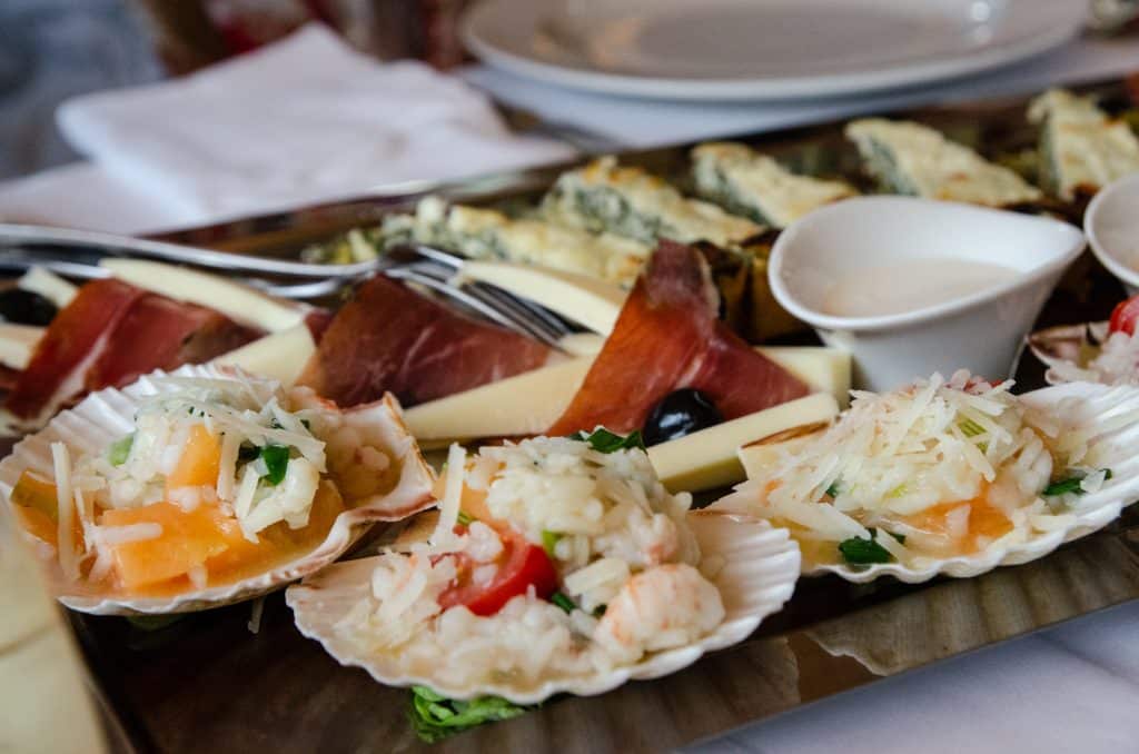 Scallops shells filled with a mix of seafood, rice, and vegetables.