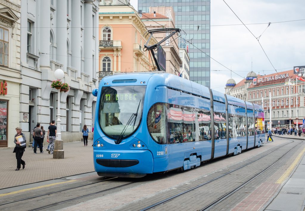 A bright blue tram heading down the street in Zagreb.