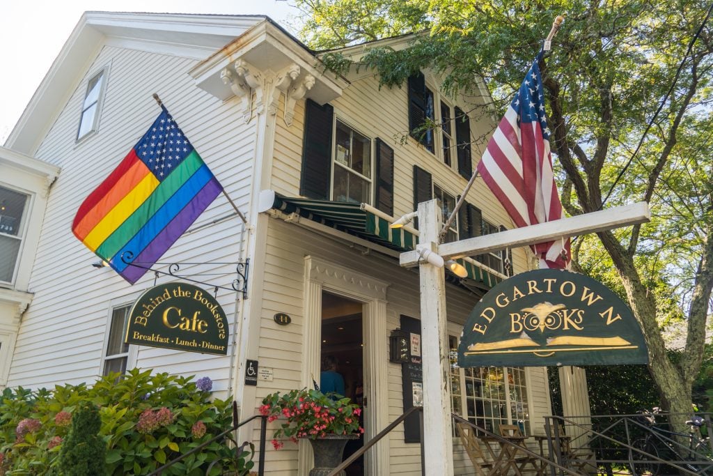 A stately white home turned into Edgartown Books bookstore, flying a rainbow pride American flag.