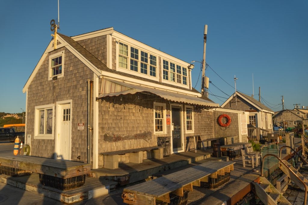 A clapboard fishing cabin light up in bright golden light at sunset.